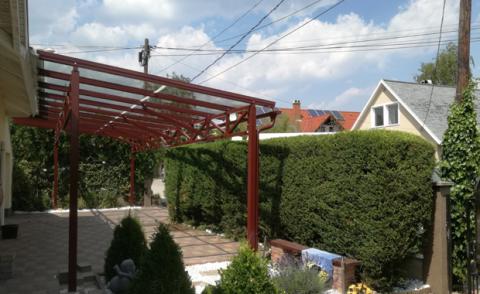 Porfestett acél tartószerkezet rácsostartóval + ragasztott biztonsági üveg fedéssel készült autóbeálló