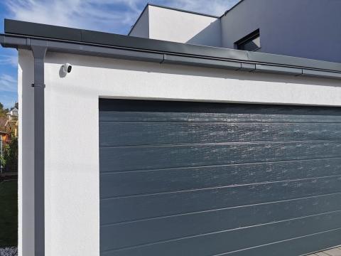 Zárt garázs szendvicspanel tetővel. Könnyűszerkezetes megoldás, elektromos garázskapuval.