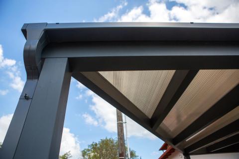 Napelemekkel fedett, extra hosszú, négy állásos kocsibeálló rétegragasztott fa szerkezettel.