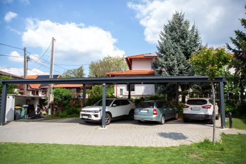 Napelemekkel fedett, extra hosszú, négy állásos kocsibeálló rétegragasztott fa szerkezettel.